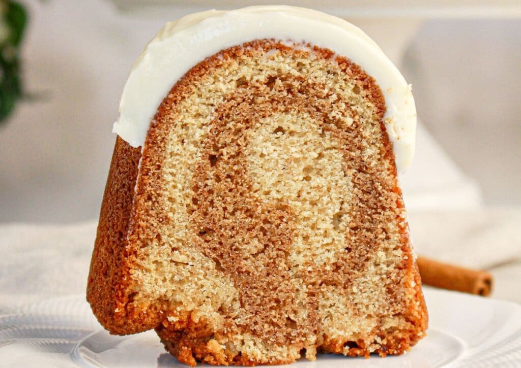 Slice of cinnamon roll bundt cake being removed from cake.