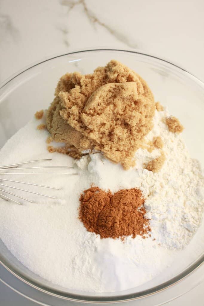 Brown sugar, cinnamon and sugar being mixed in a large bowl.