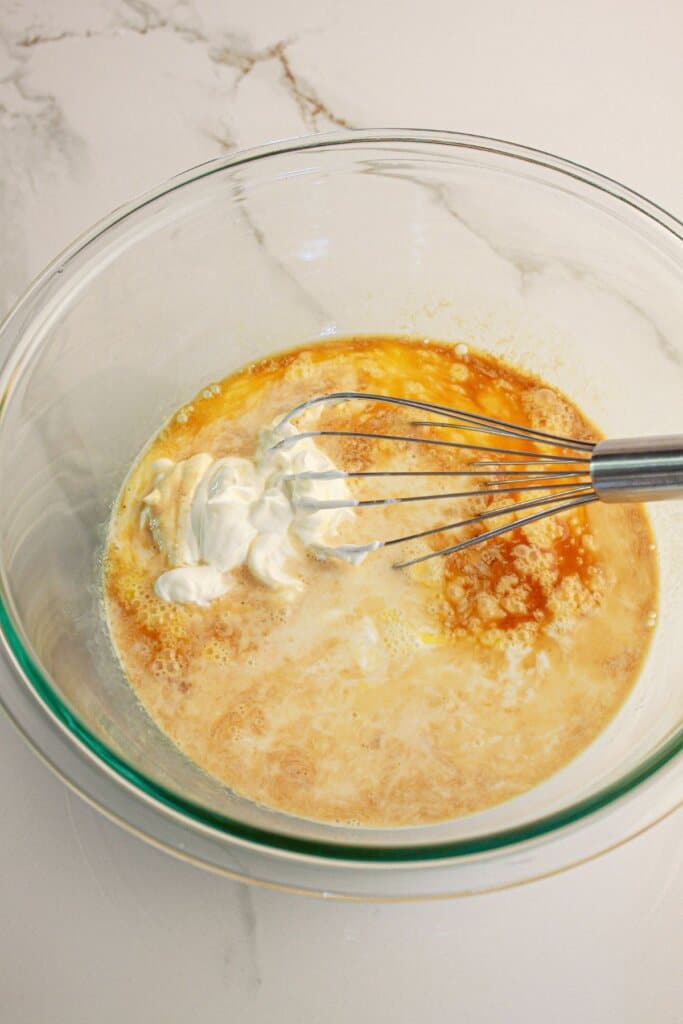 Wet ingredients being mixed in a glass mixing bowl.