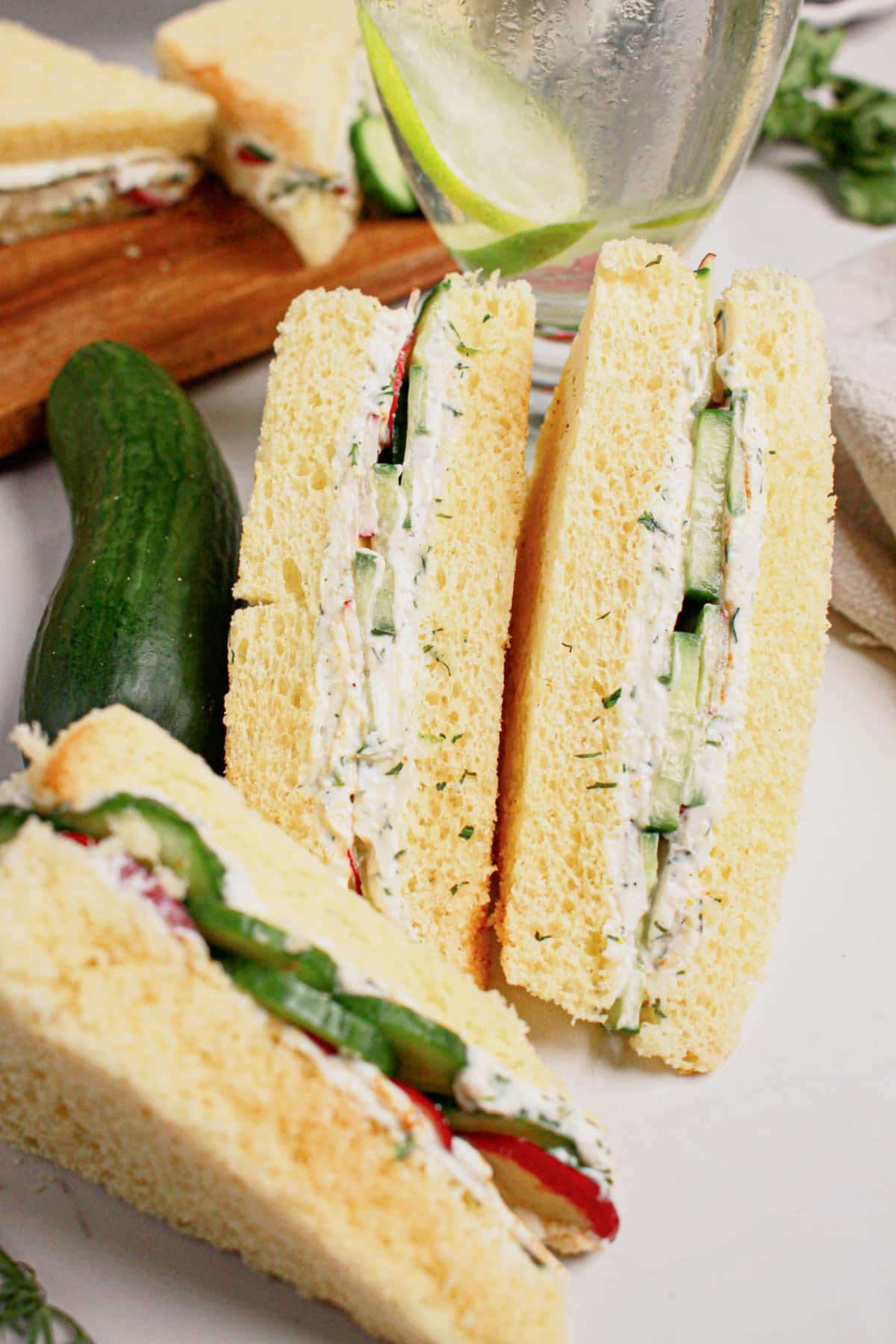 Two cucumber sandwiches stacked on a plate.