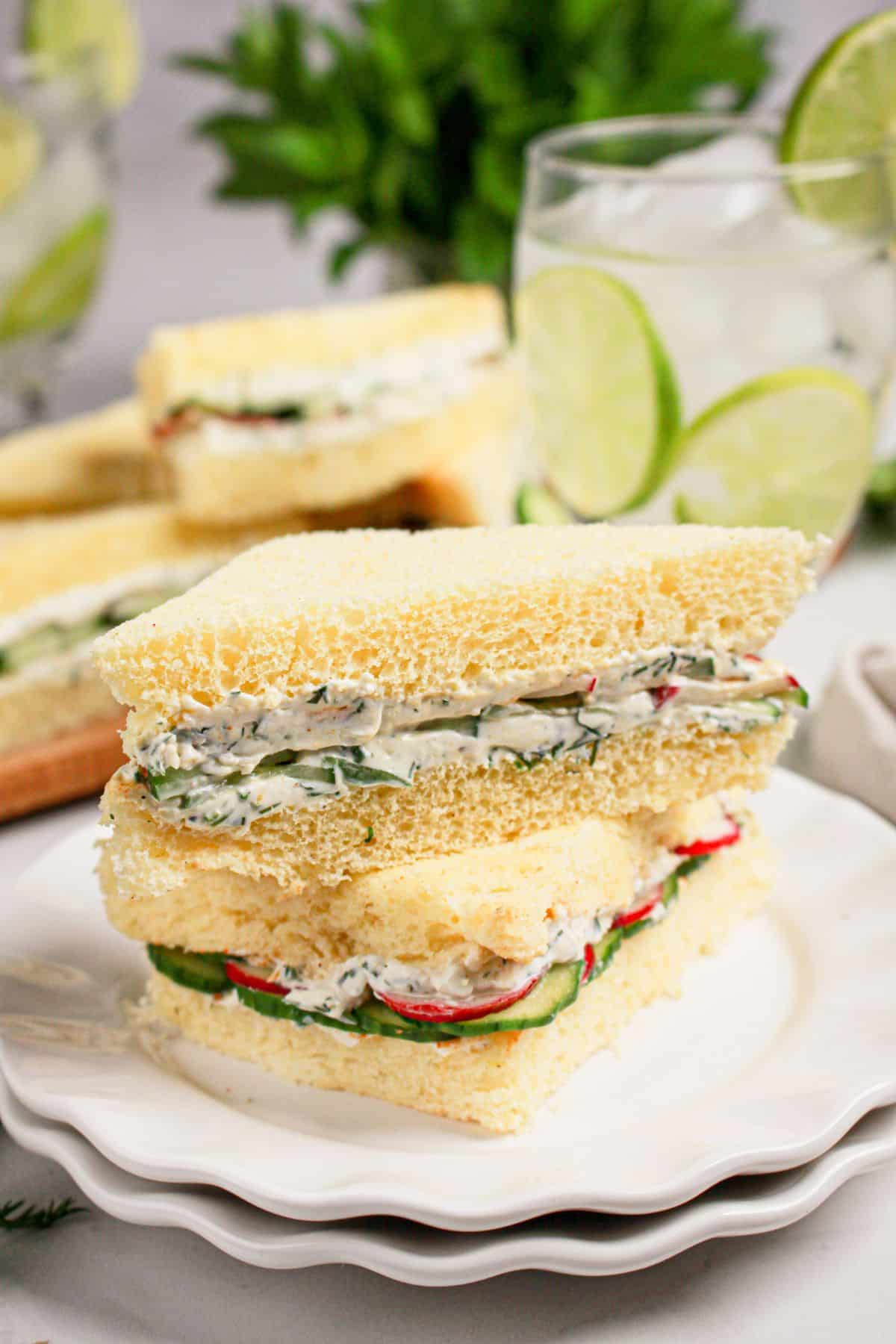 Two cucumber sandwiches stacked on a plate.