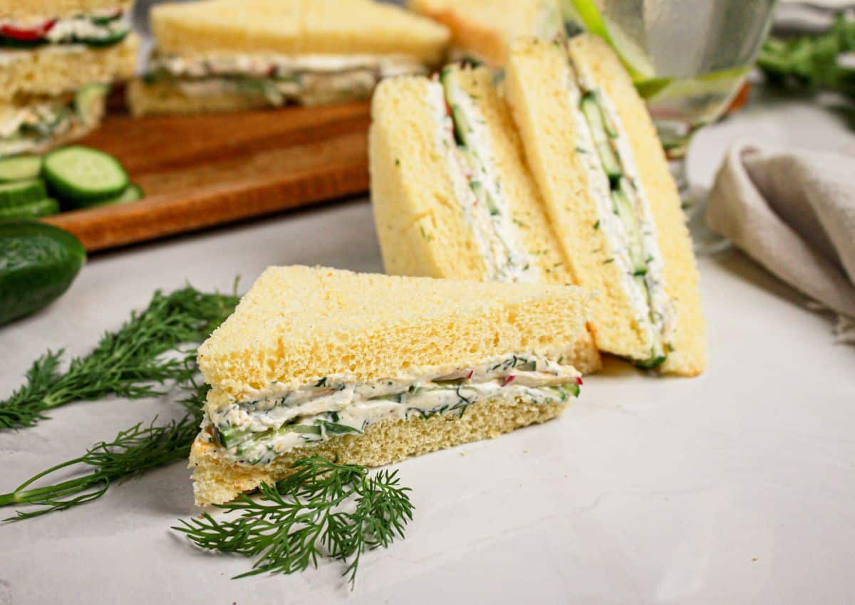 Two cucumber sandwiches stacked on a plate.