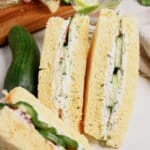 Two cucumber sandwiches stacked on a plate.