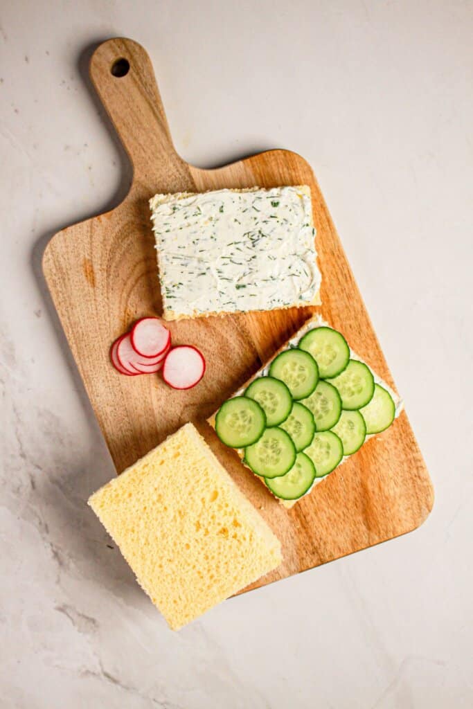 Vegetable slices being added on top of a slice of bread.