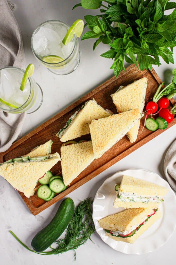 Cucumber sandwiches on a wooden serving platter.