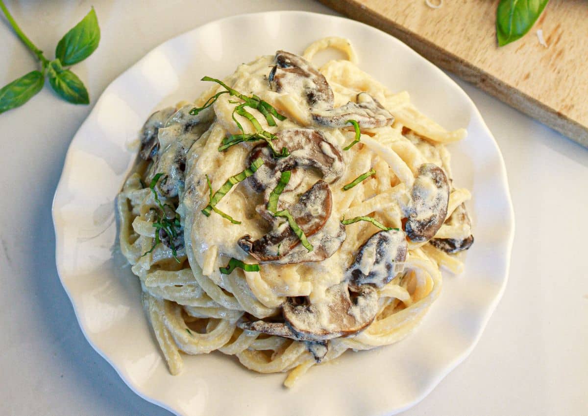 White plate full of a serving of creamy mushroom linguine.