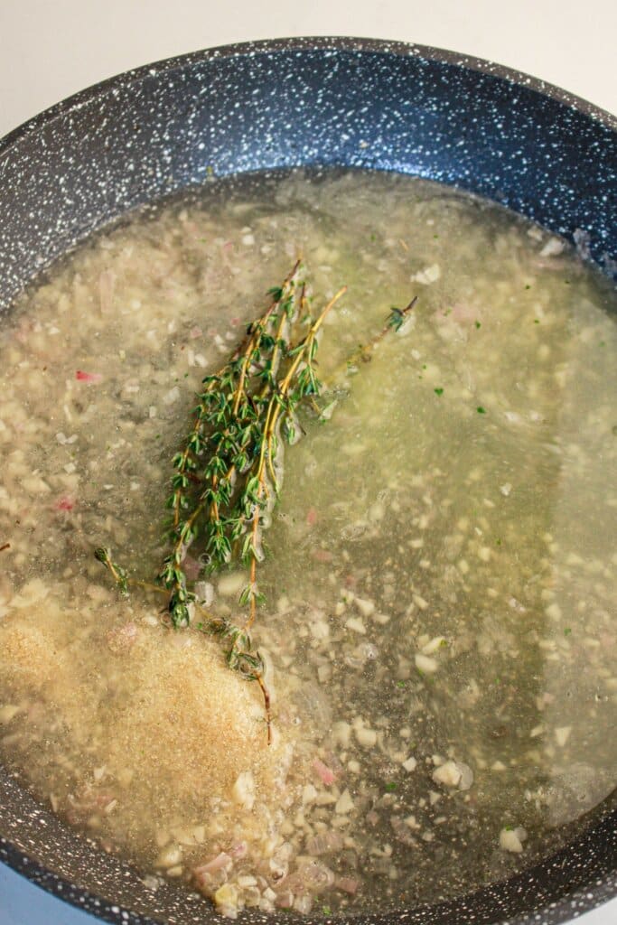 Broth, garlic, and shallots in a skillet.