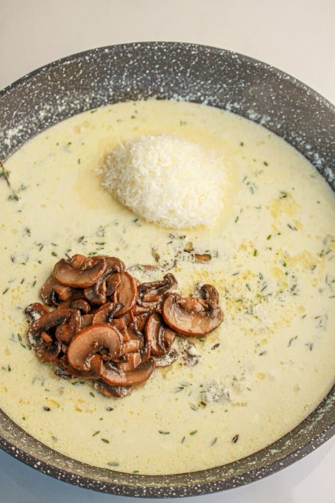 Mushrooms and cheese being added to a skillet.