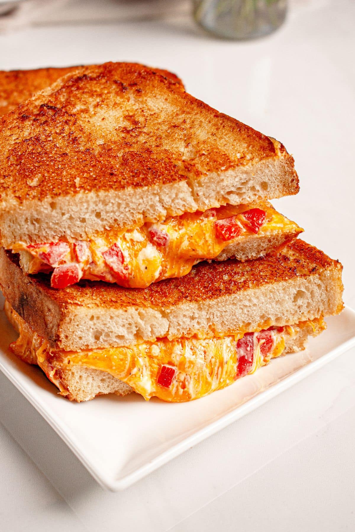 Three pimento grilled cheese sandwiches stack on top of each other.