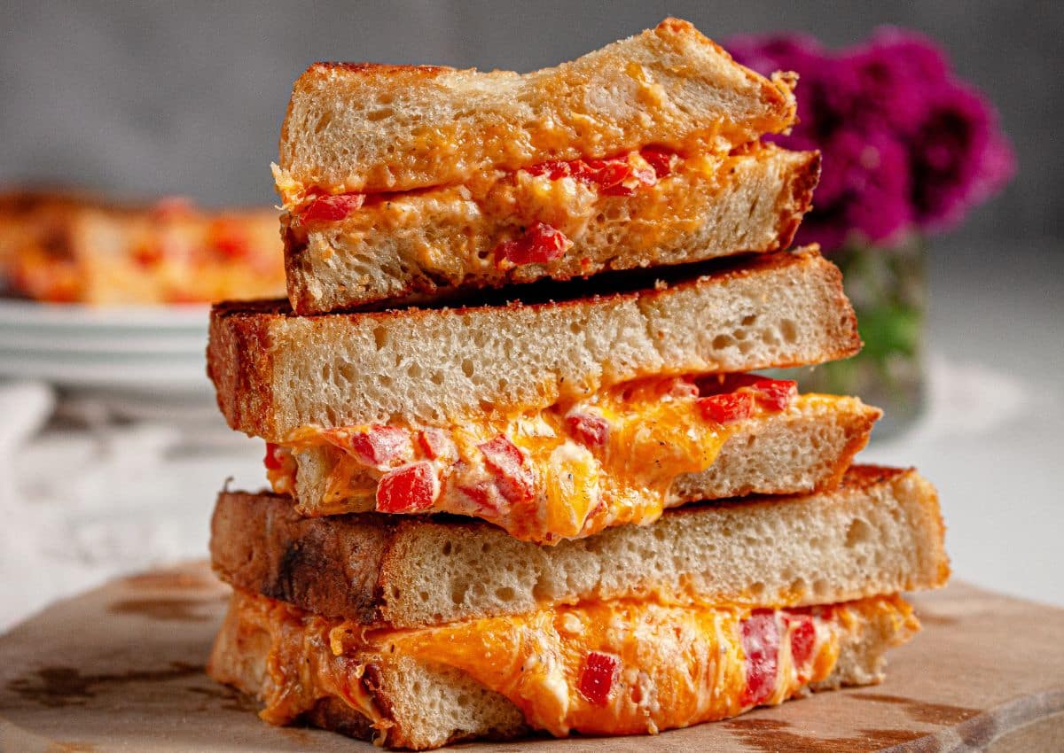 Three pimento grilled cheese sandwiches stack on top of each other.