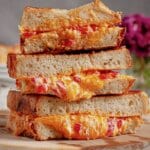 Three pimento grilled cheese sandwiches stack on top of each other.