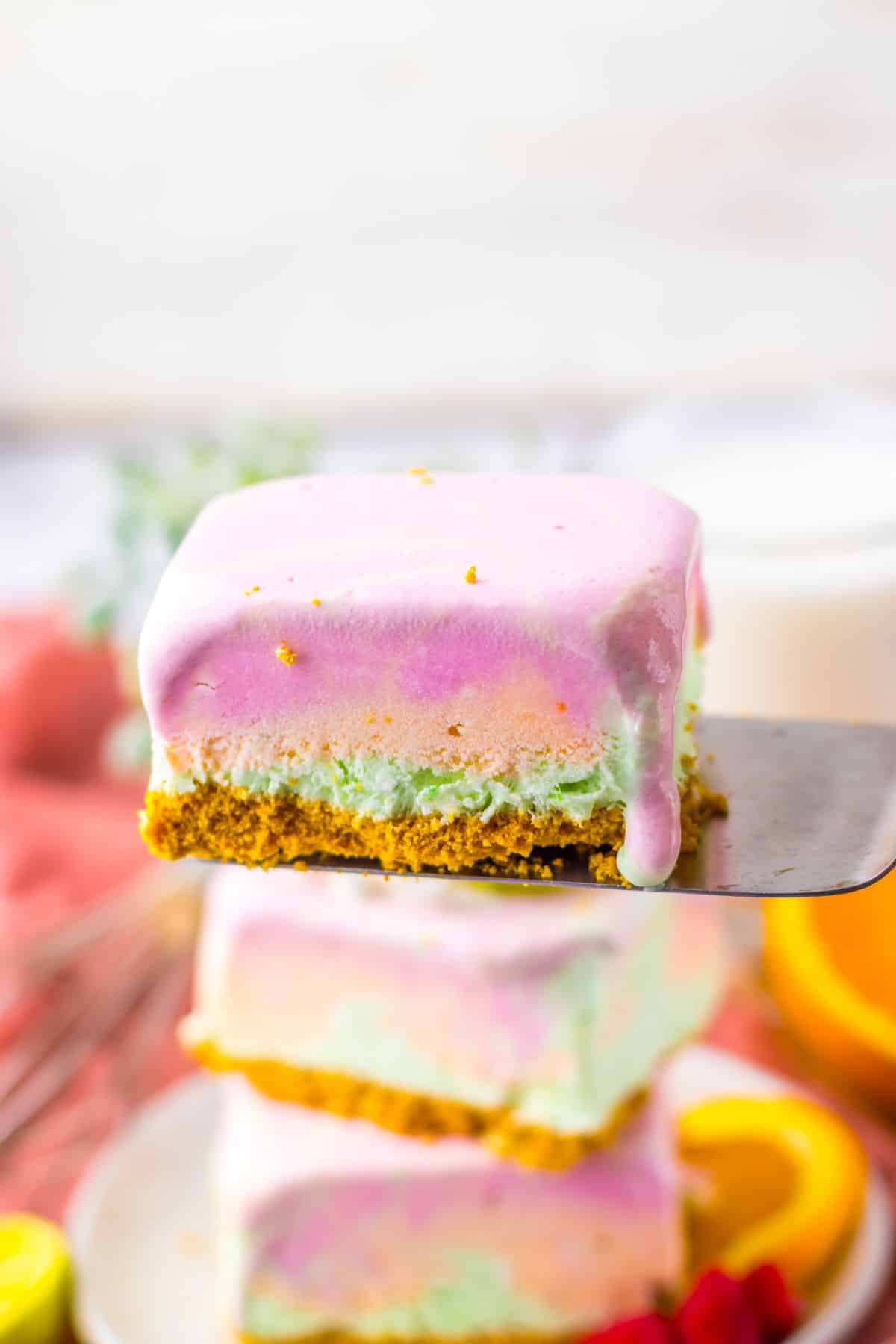 Slice of rainbow sherbet bar on a spatula.