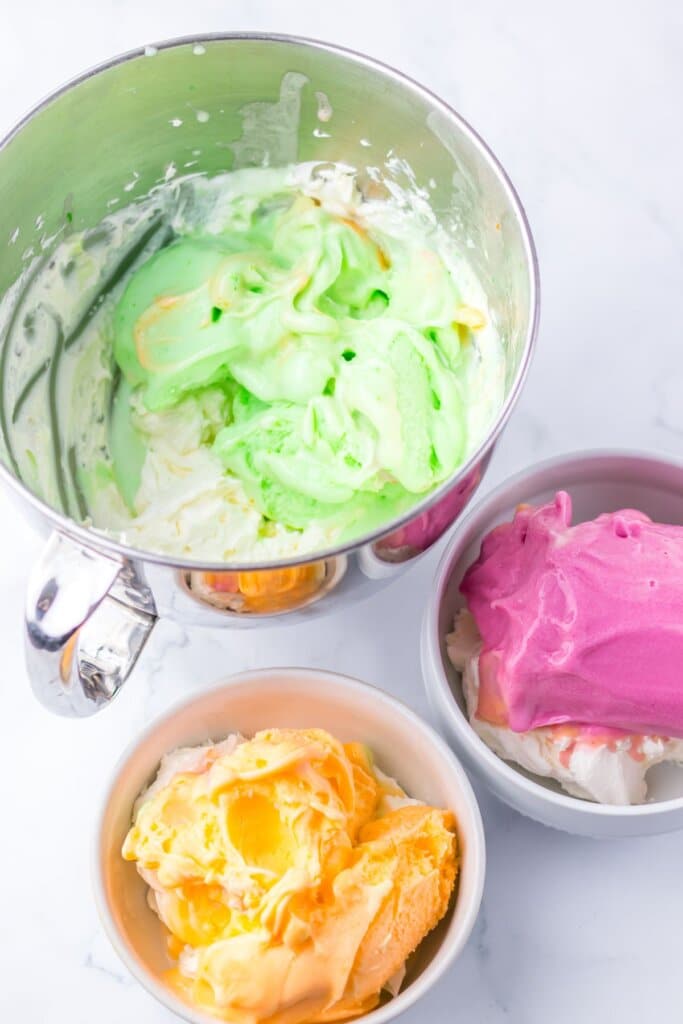 Three bowls of green, orange and pink ice cream.