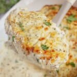 Sour cream covered chicken breast held on a spoon.