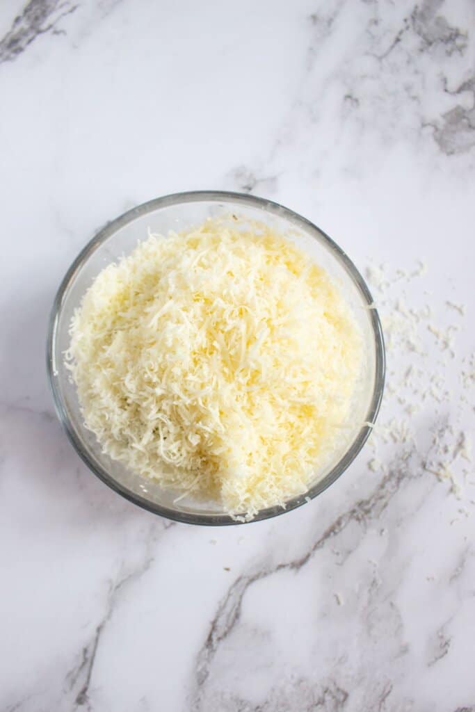 Shredded cheese in small glass bowl.