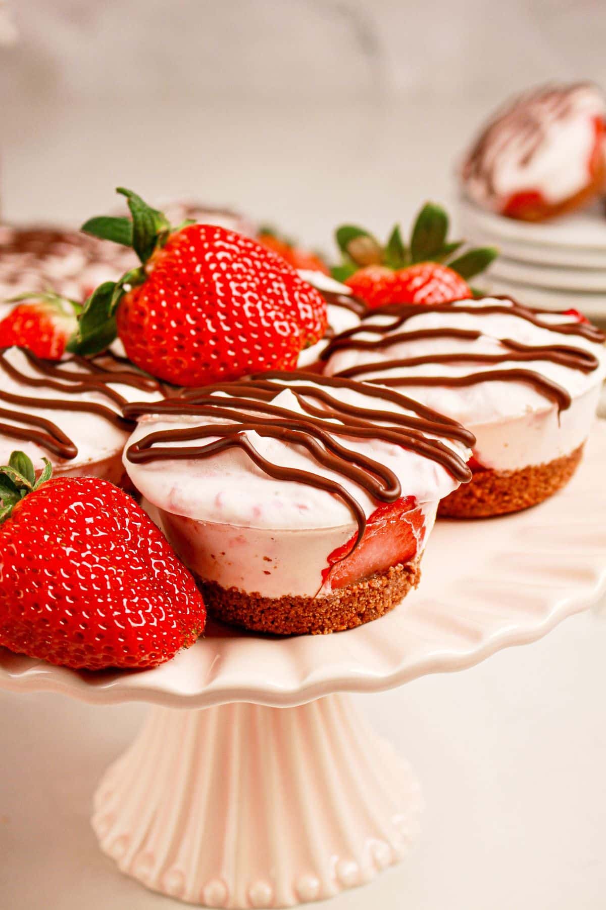 Strawberry cheesecake cups on a white cake plate.