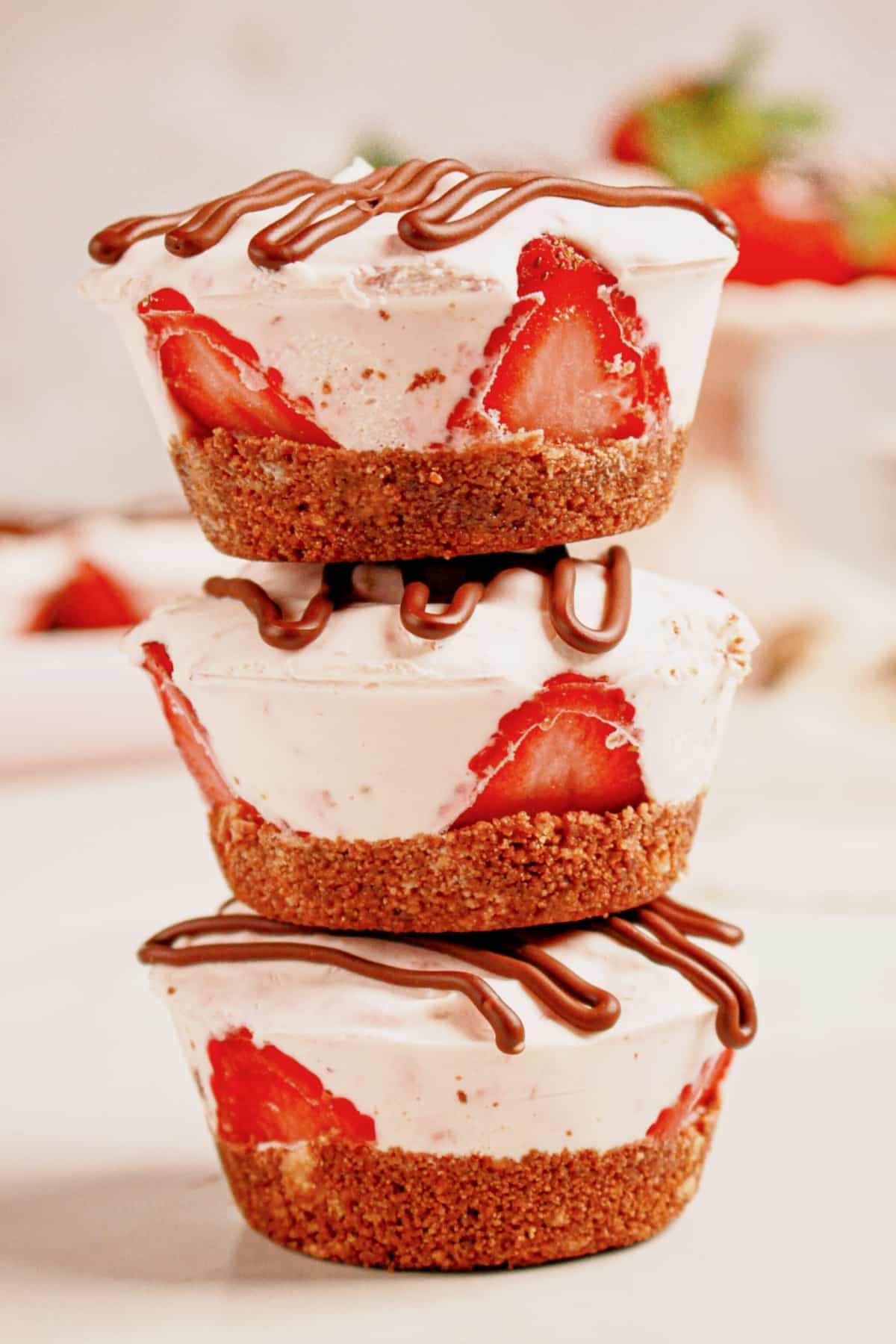 Three strawberry cheesecake cups stacked on top of each other.