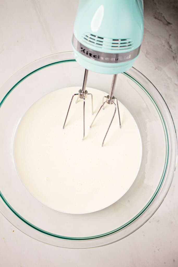 Heavy cream being mixed in a glass bowl.