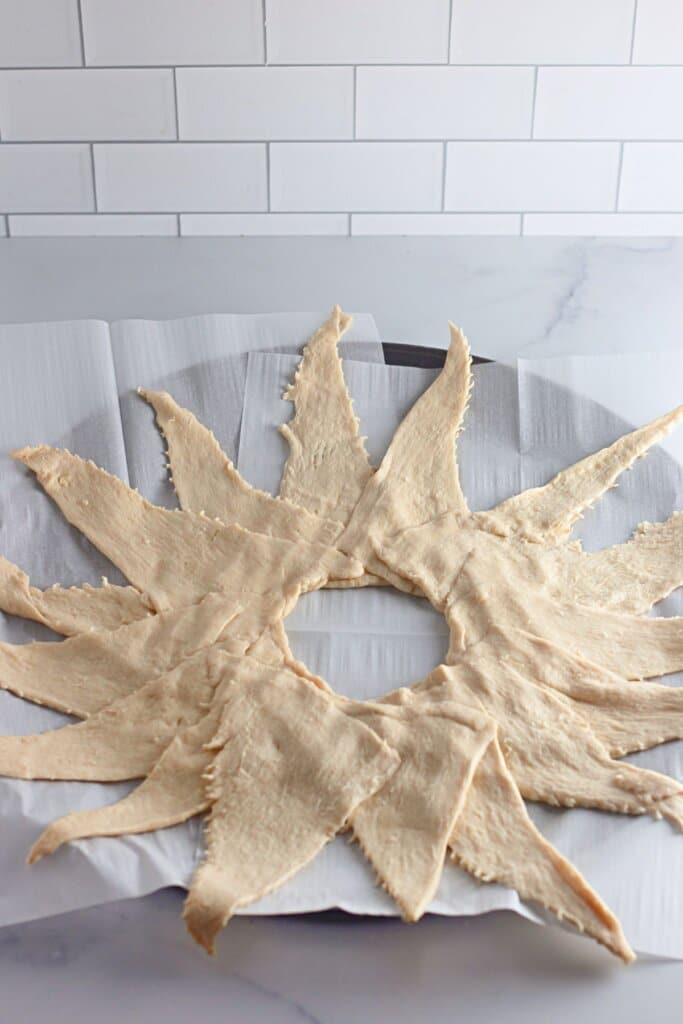 Dough is being laid out in a circle on a baking sheet.