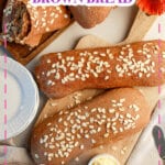 Two loaves of brown bread on a wooden cutting board.