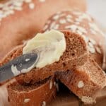 Butter being spread on a slice of bread.