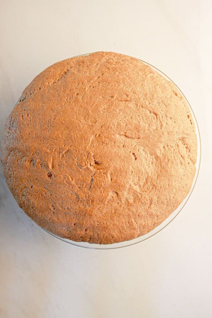 Dough rising in a glass mixing bowl.