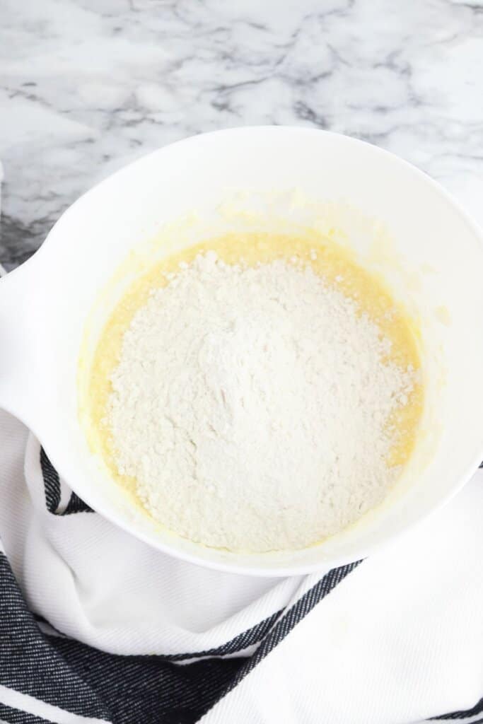 Dry ingredients being added to batter in a bowl.
