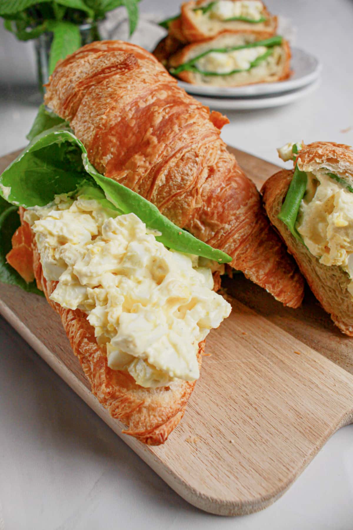 Egg salad sandwiches on a wooden cutting board.