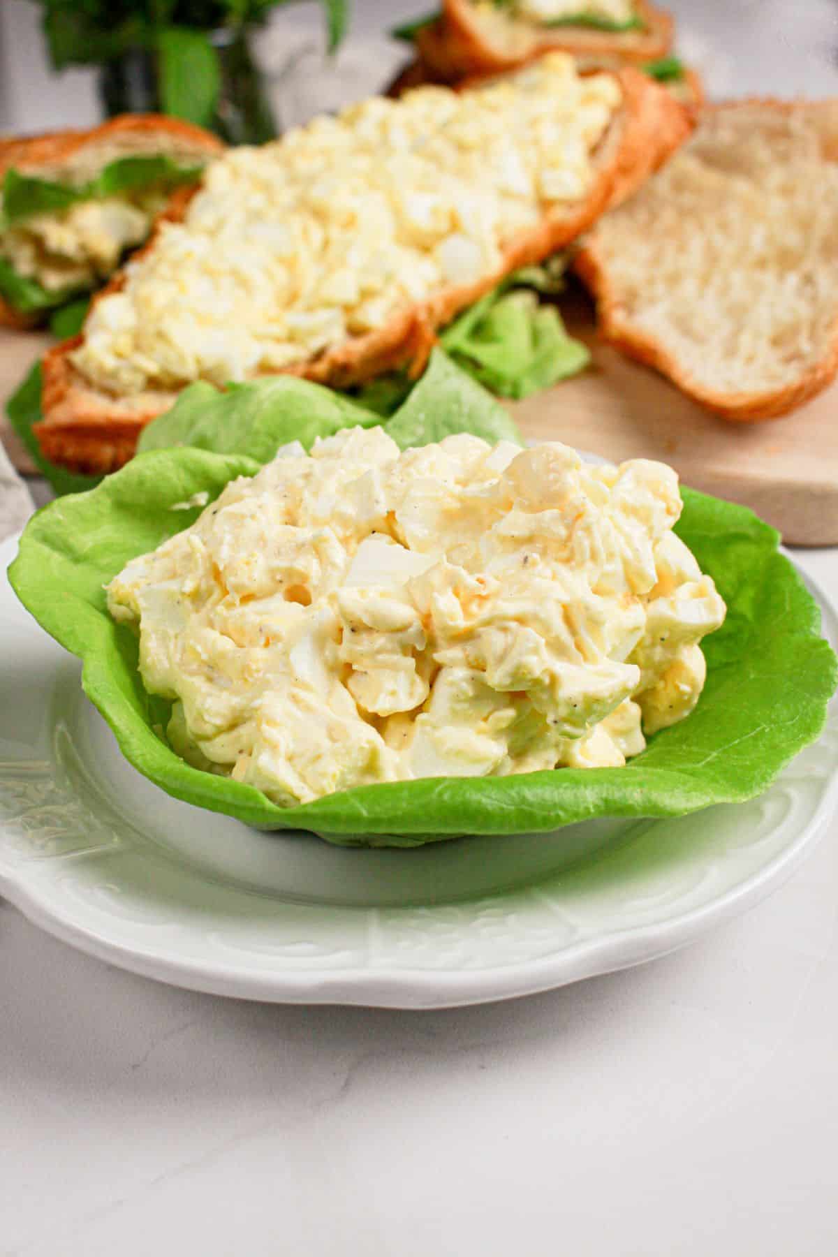 Lettuce cup filled with egg salad on a plate.