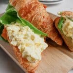 Egg salad sandwiches on a wooden cutting board.