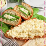 Egg salad sandwiches on a wooden cutting board.