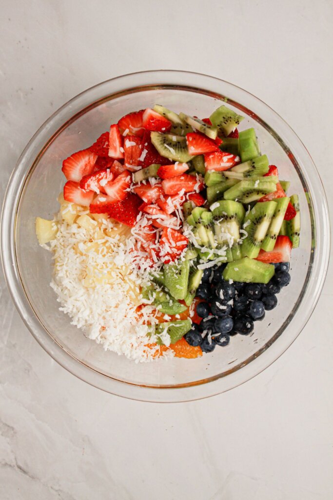 Fruit and shredded coconut in a glass bowl.