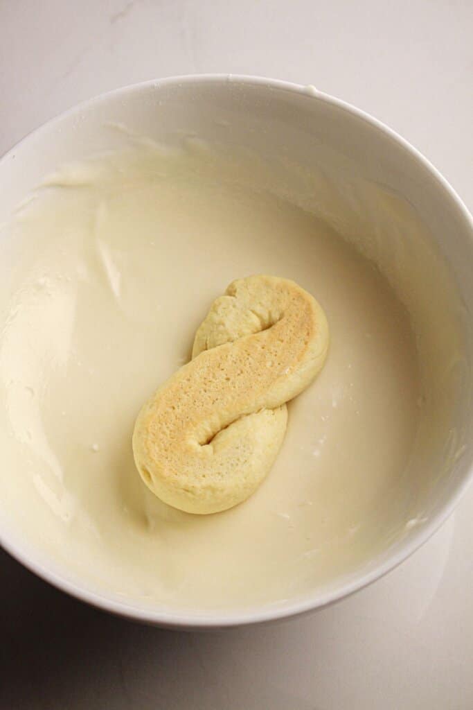 A cookie is being dipped in icing in a bowl.
