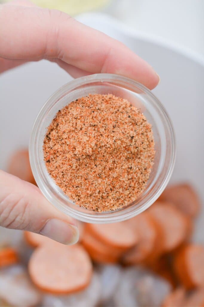 Seasoning being sprinkled on top of meat.