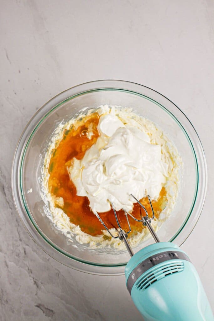Sour cream and maple syrup being mixed in a glass bowl.