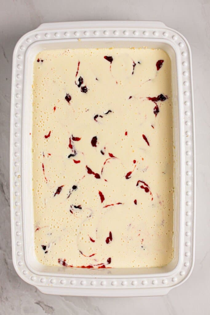 Raspberry being spread into dessert batter.