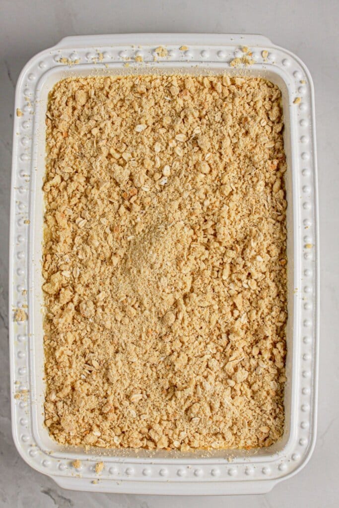 Topping being sprinkled on top of the baking dish.