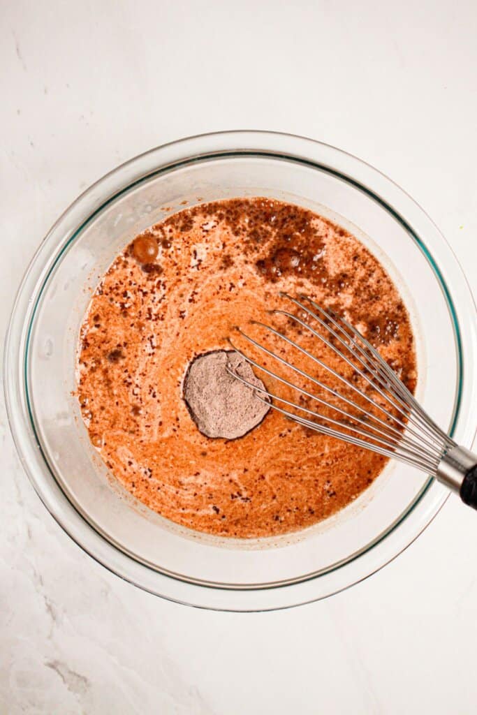 Chocolate pudding being mixed in a glass bowl.