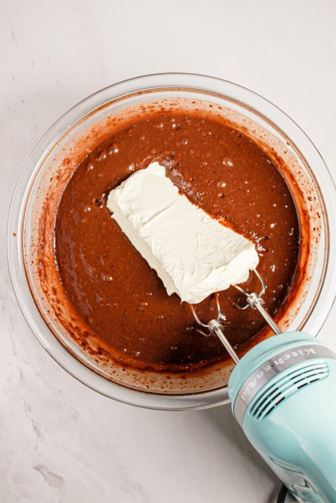 Cream cheese being mixed into chocolate pudding.