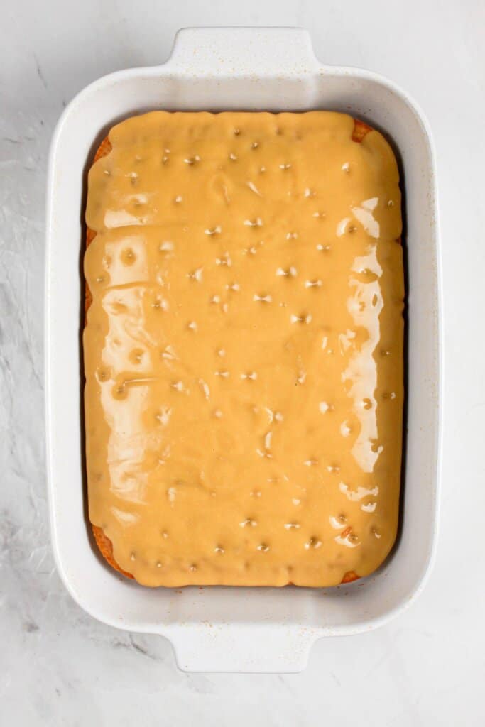 Pudding being poured on cake with holes in it.