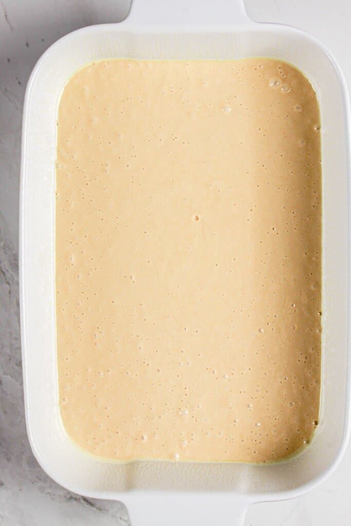 Batter in a white baking dish ready for the oven.