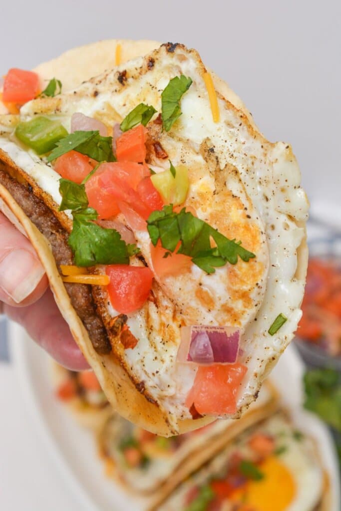 A breakfast taco held in a woman's hand.