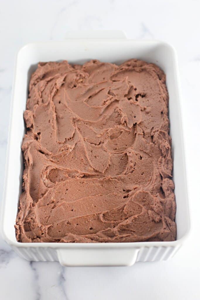 Batter being spread in a white baking dish.