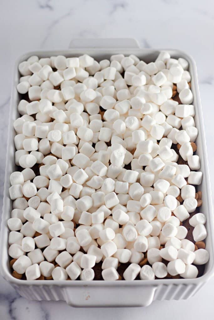 Marshmallows being sprinkled on taking a baking dish.