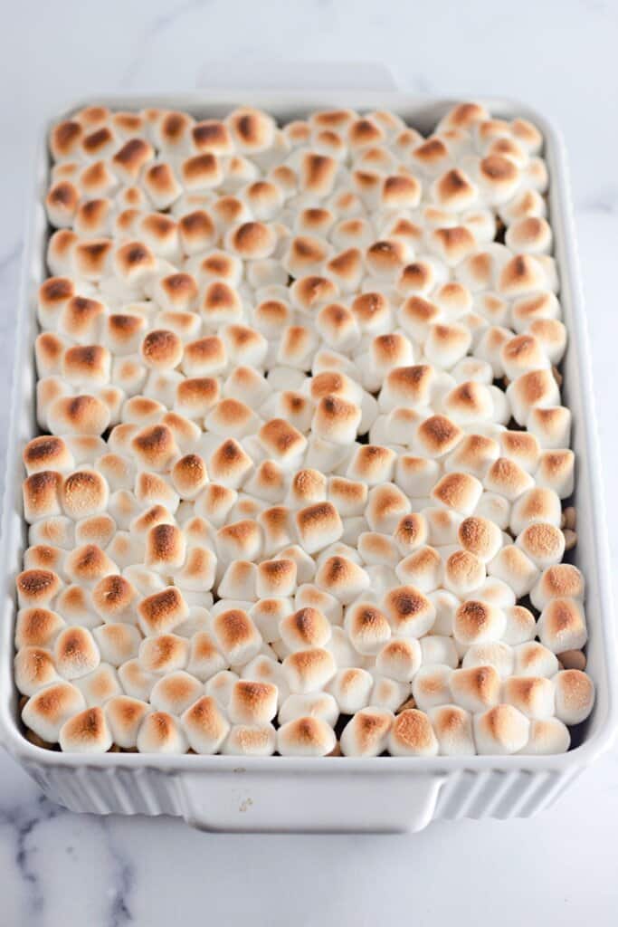 Toasted marshmallows on top of dessert in a white baking dish.