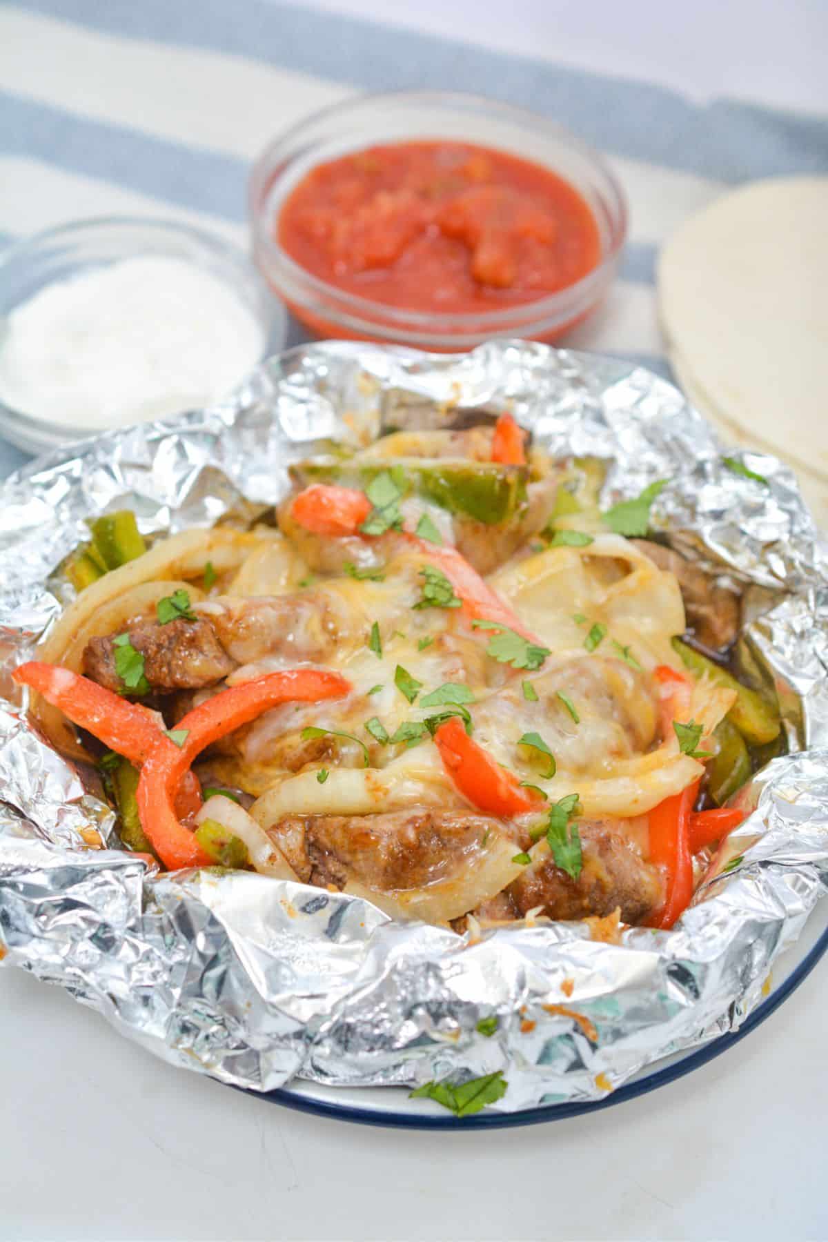 Steak fajitas foil packet on a plate.