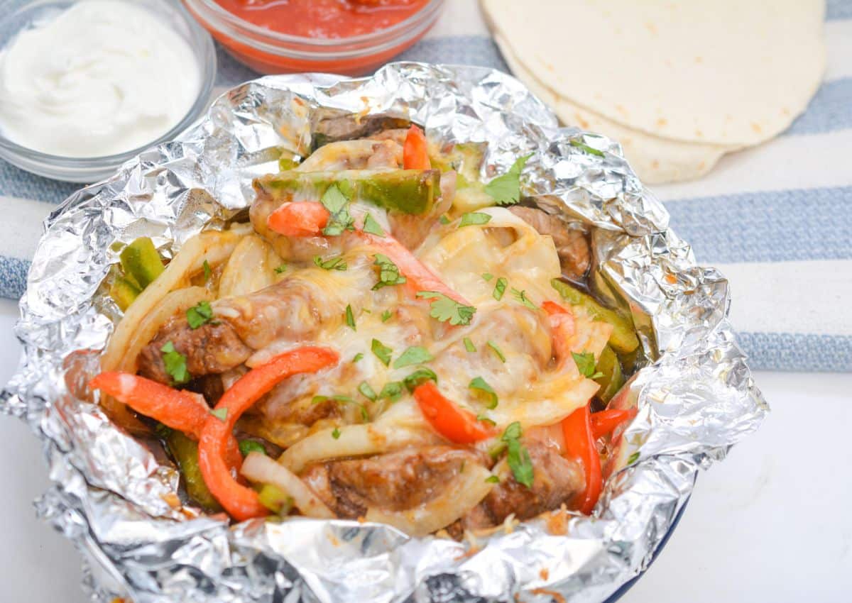 Steak fajitas foil packet on a plate.