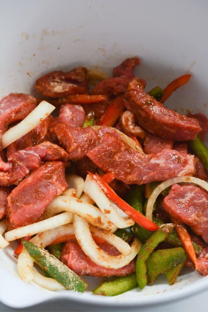 Meat, veggies, and seasonings in a mixing bowl.