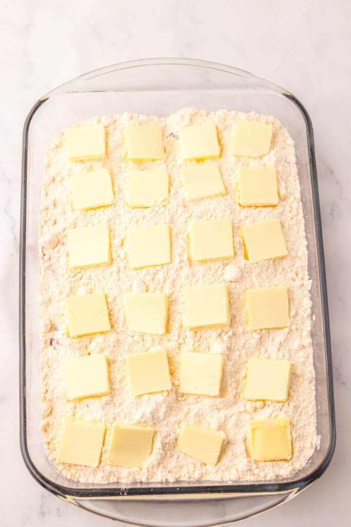 Butter being spread on top of dessert in a baking dish.
