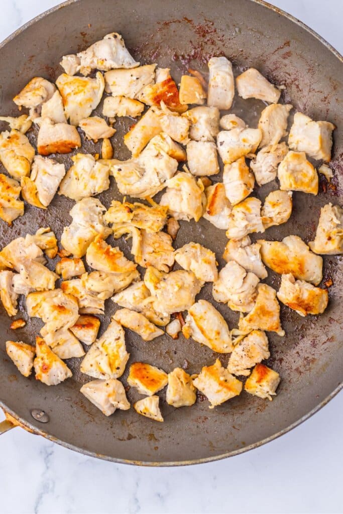 Chicken pieces being cooked in a skillet.